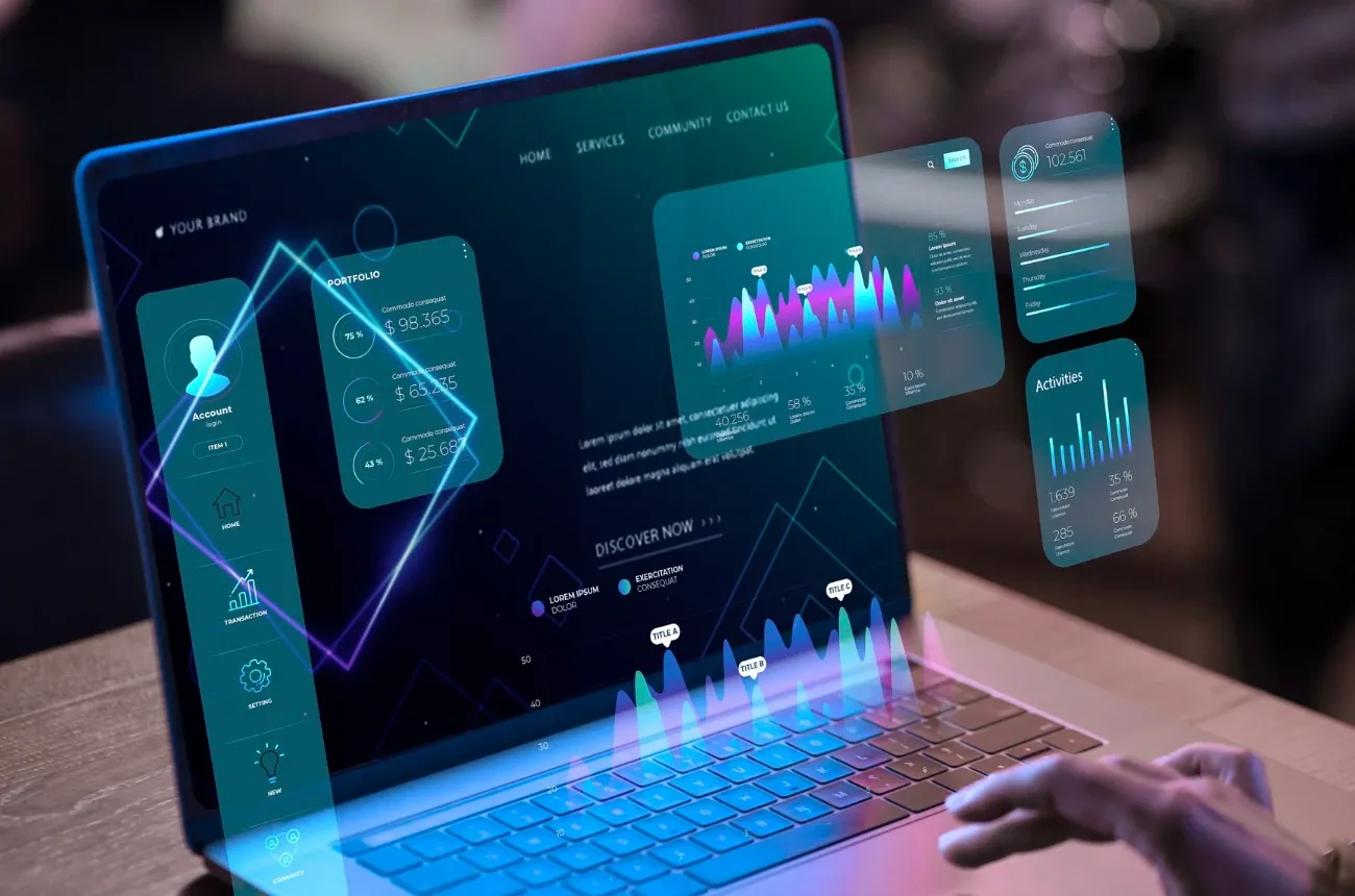 A hand typing on a laptop with glowing holographic dashboards and charts floating above the screen