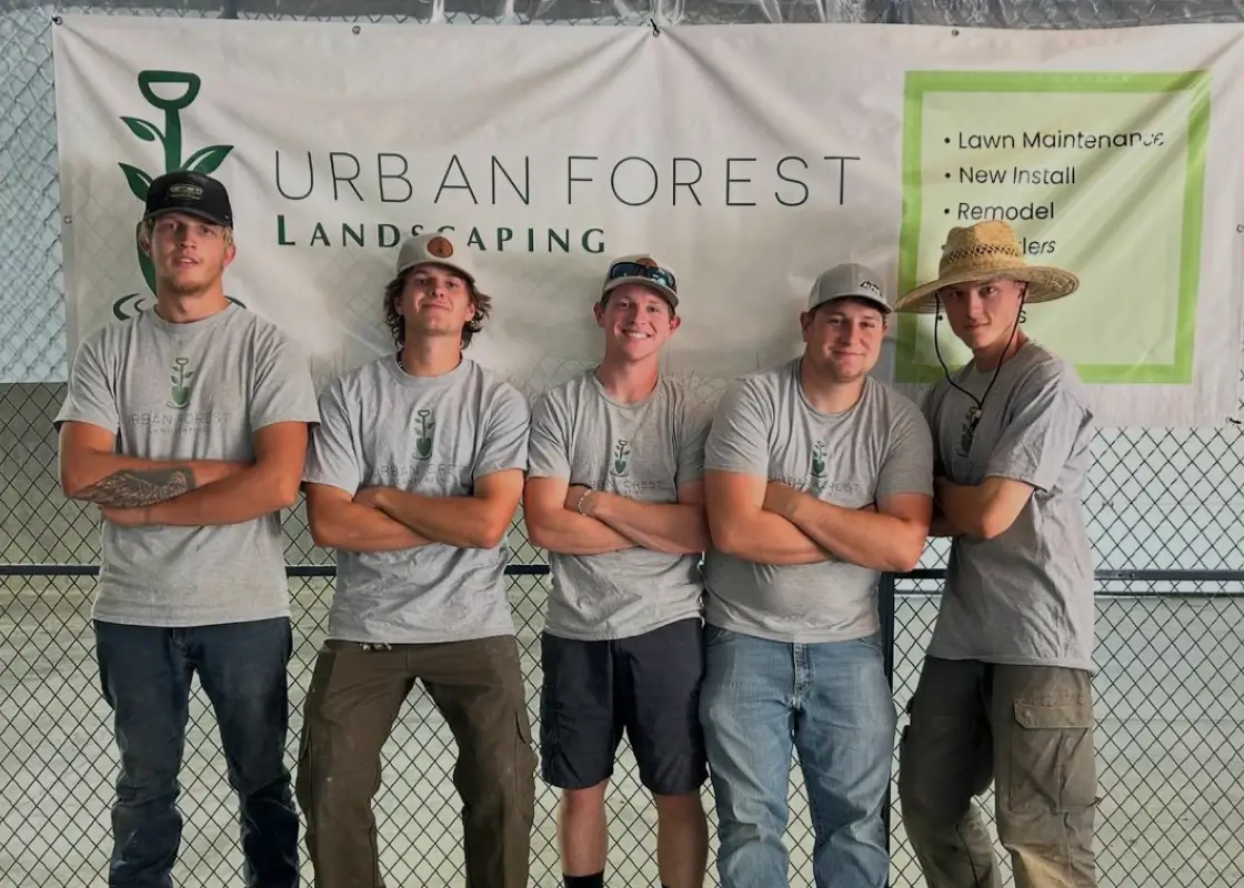 Urban Forest Landscaping Team, five men posing in front of their banner